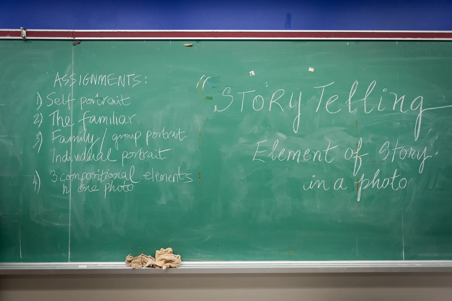 A green classroom chalkboard with handwritten assignments and the title “Story Telling: Element of Story in a Photo.”